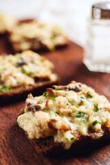 Rye bread toast with smoked mackerel, cream, cheese and green onion on wooden cutting board. Delicious appetizer, tapas. Selective focus - 544612203