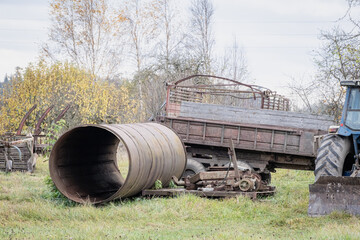 Obraz premium Old agricultural tractor on the side of the road. trailer cart to the tractor on large wheels 