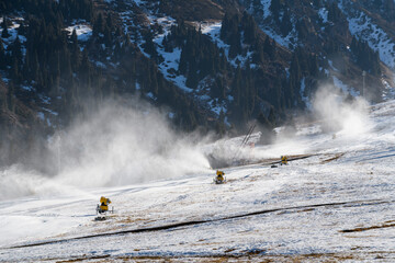 Snow guns prepares ski slope in mountain ski resort. Snow cannon working. Snowmaking.