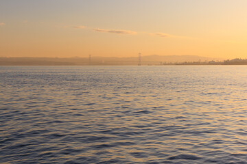 Orange sunset sky and sun over the sea. Water surface and outlines on the horizon.