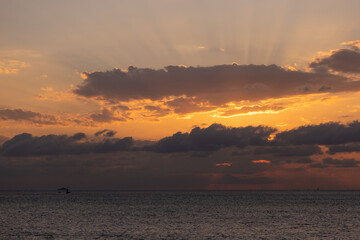 Orange sunset sky and sun over the sea. Water surface and outlines on the horizon.