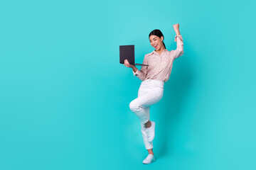 Full body portrait of delighted thai girl raise fist achievement use netbook isolated on teal color background