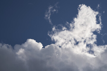 A piece of a blue sky with many clouds around. Midday cloudscape in the summer sky.