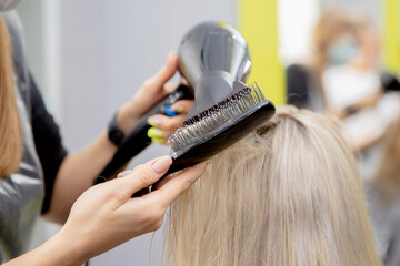 Master hairdresser dries client hair with hairdryer, keratin scalp care close-up