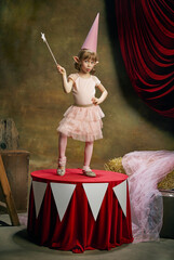 Magic. Little cute girl, kid in image of magical elf posing over dark circus backstage background....