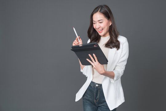 Young asian woman confident manager worker use modern technology digital tablet work remote distance isolated grey color background. Beautiful woman using smartphone. Lifestyle concept.