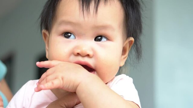 Asian baby girl is 9-month-old sucking finger, smiling and happy, to Asian baby and development concept.