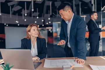 Two multiethnic colleagues working together on project in modern office