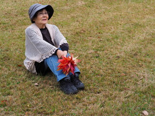 紅葉したカエデを持つ高齢日本人女性