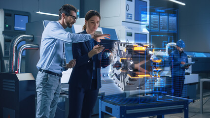 Factory Office Facility: Chief Engineer Holds Tablet Computer, Shows Augmented Reality Model of an...