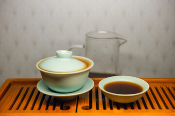 Brewing Chinese tea in ceramic gaiwan during the tea ceremony close-up. Gaiwan and other tea tools for the ceremony. 