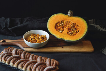 fresh cut pumpkin on wooden board with cinnamon roll bread on black background  - 544642072