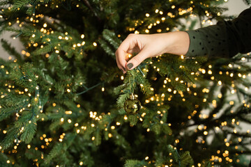 Christmas ball in hand near the Christmas tree with a garland