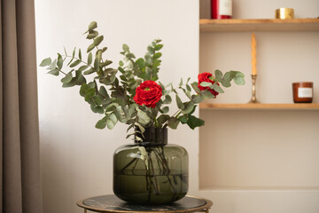 Silver eucalyptus with red roses in a glass vase