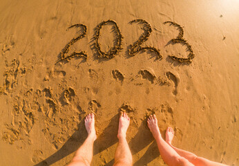 tropical New Year 2023 written in golden sand on the beach