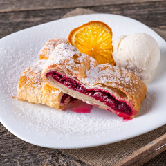 Sweet cherry strudel with ice cream on a plate