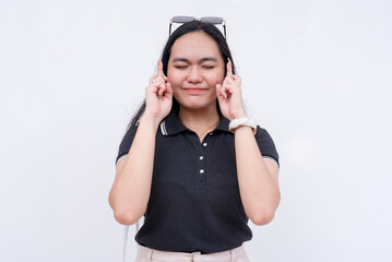 A young asian woman crosses her fingers and closing her eyes hoping and waiting for a great result....