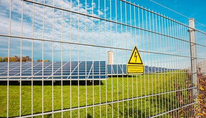 Danger high voltage attention sign on the exterior electric fence. solar power station. panels in...