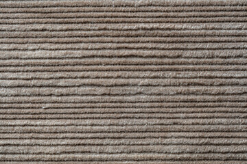 Texture backdrop of beige colored corduroy fabric cloth. Corduroy retro fabric background or texture. Closeup view