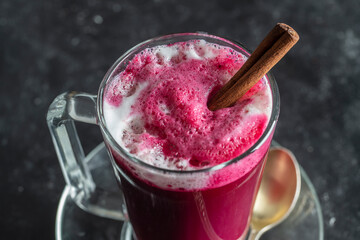 Beetroot vanilla latte from fresh beetroot juice blended with vanilla and milk in a transparent cup on the table in cafe, closeup. Trendy healthy drink