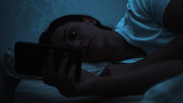 Woman gets tired while using smart phone in bed