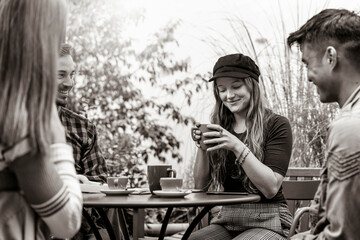 People group drinking latte at coffee bar garden - Friends talking and having fun together at hostel dehors - Lifestyle concept with happy guys and girls at open air cafe - Black and white editing