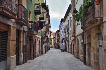Calle del municipio de Balmaseda vacía con casas de piedra, casas de colores y plantas en los balcones