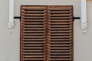 Closed Mediterranean rustic window shutter made of wood on the wall of an old traditional home