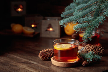 Tea with lemon and small Christmas lanterns on a wooden table.