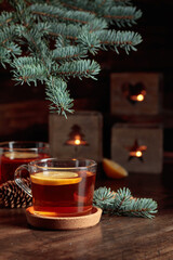 Tea with lemon and small Christmas lanterns on a wooden table.