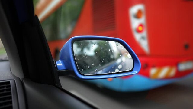 Slow motion video of a modern blue car right side mirror, while driving on a street.