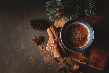 Mug of hot coffee with milk and Christmas spices on rustic background. Copy space - 544670013