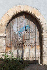 Very old timeworn wooden door in arched stone doorway