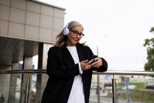 woman economist for contract and claim work, in headphones on the terrace of the office outside answering messages on a mobile phone, investment analysis and valuation models to support the rationale