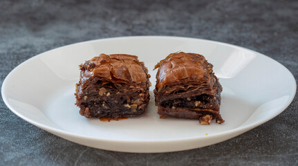 Chocolate baklava in a white plate. Turkish style chocolate baklava presentation and service. Horizontal view.