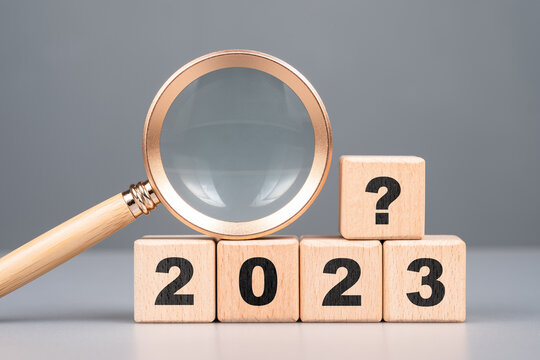 2023 wood cubes with question symbol and magnifying glass, analysis what will happen in 2023, product review and forecast, trend concept
