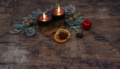 Weihnachtshintergrund: Arrangement mit brennenden Kerzen, Zimtstangen, Nüssen und Äpfeln auf einem alten schäbigen Brett.