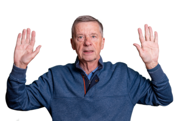 Senior adult male with hands raised and worried expression as he surrenders to his fate