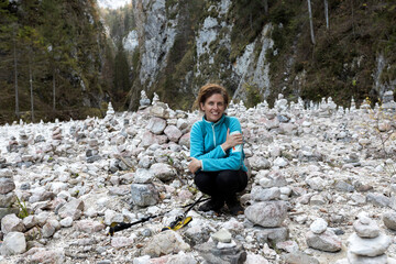 Serene Mid Adult Woman Hiker Happy on a Hike trough a Valley of Stack Stone Towers by Hikers -...