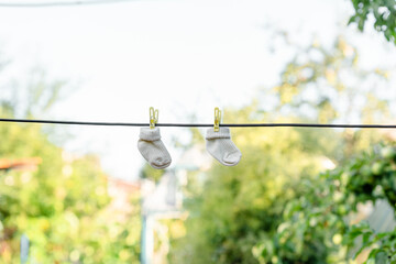 Socks for a newborn are dried on a rope in a green garden