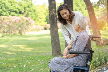 Caregiver help and care Asian senior or elderly old lady woman patient sitting and happy on wheelchair in park, healthy strong medical concept.