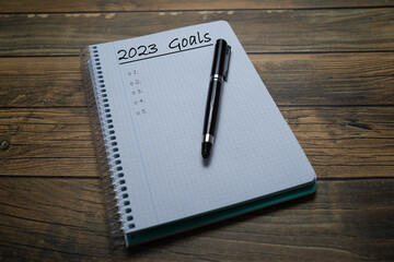 Notebook sheet written 2023 to put the resolutions and objectives of the year, with a pen and wooden background.