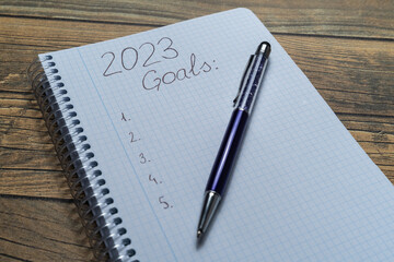 Notebook sheet written 2023 to put the resolutions and objectives of the year, with a pen and wooden background.