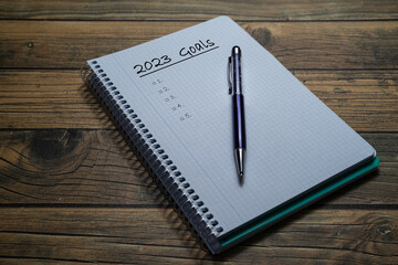 Notebook sheet written 2023 to put the resolutions and objectives of the year, with a pen and wooden background.