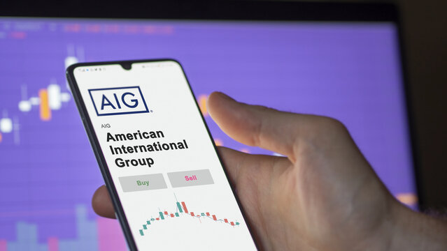 AIG investor's analyzing the American International Group AIG stock on screen. A phone shows the prices to invest