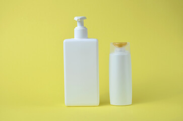 Two white bottles for soap on a yellow background.