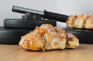 St. Martin's croissant and gym dumbbell barbell weight plates. Rogal marciński or świętomarciński. Traditional polish pastry with poppy-seed filling and nuts. Healthy fitness diet choice concept.