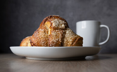 Fresh traditional polish pastry with poppy-seed filling and nuts. St. Martin's croissant. Rogal marciński or świętomarciński and white ceramic coffee cup or tea mug. - obrazy, fototapety, plakaty