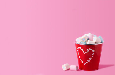 Sweet marshmallows  in red bucket on pink pastel background. Place for text. Postcard for birthday, Valentine day.