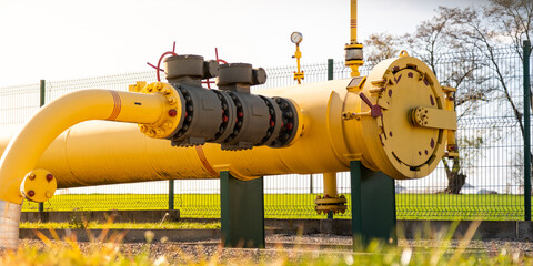 Big gas pipe - natural gas transport system. Transmission infrastructure coming from the ground, yellow pipes with a safety valve